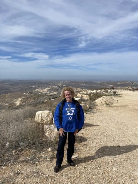 L’écrivain se tient sur une colline, dans la communauté juive d’Yitzhar (יצהר) avec une vue panoramique sur Israël jusqu’au rivage de la mer Méditerranée - Photo : Nurit Greenger